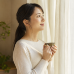 窓辺で穏やかな表情をたたずむ30代の日本人女性