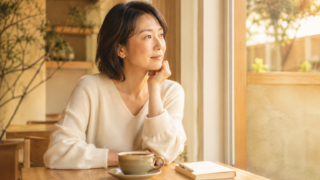 カフェで窓の外を見つめながら婚活について静かに考える30代日本人女性